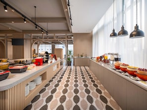 Ett modernt café med en lång bardisk, ett mönstrat golv och ett stort fönster som släpper in mycket naturligt ljus.