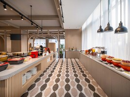 Un café moderno con una barra larga, un suelo estampado y un amplio ventanal con luz natural.