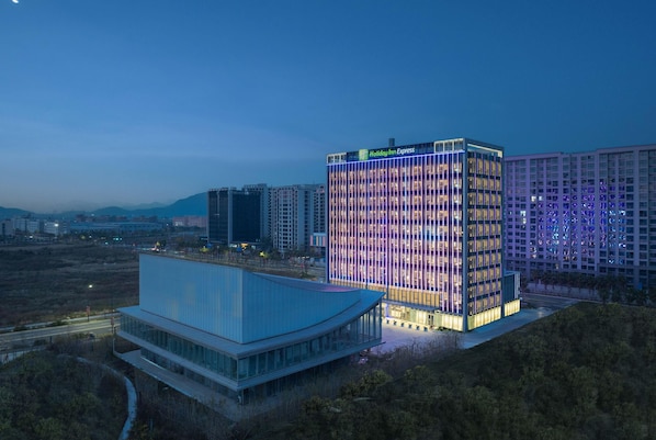 Un hôtel Holiday Inn Express au design moderne, caractérisé par une façade en verre remarquable et une terrasse sur le toit.