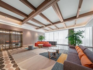 Un salon moderne doté d’un haut plafond, de grandes fenêtres et d’un mélange de canapés et de tables.