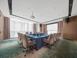 Un salón de conferencias con una larga mesa, sillas, un proyector y una pantalla grande.