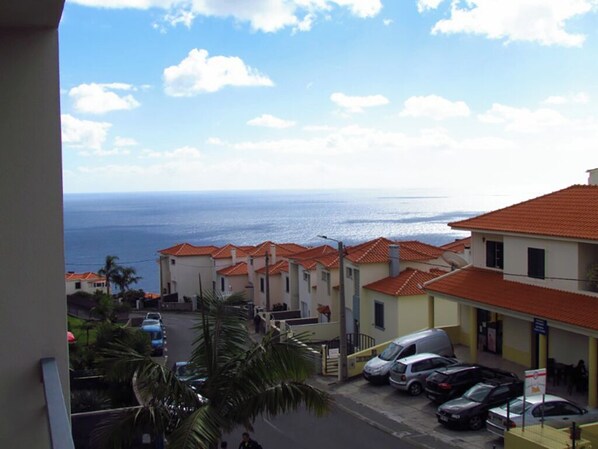 Un quartier résidentiel situé sur la côte, avec des maisons à étages, une vue dégagée sur la mer et des voitures garées.