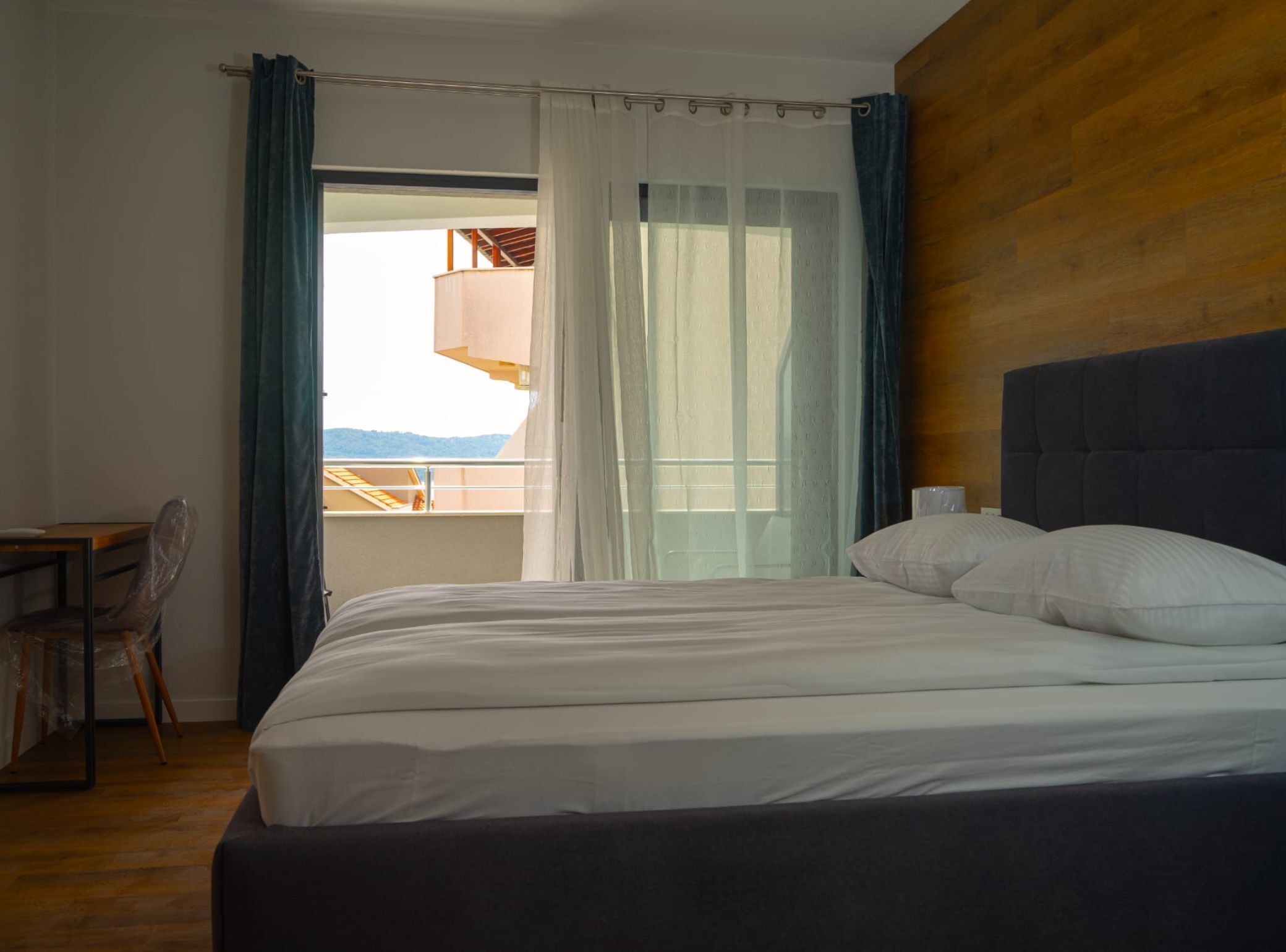Ein Schlafzimmer mit einem Bett, einem Holzkopfteil, einem Schreibtisch und einem Sessel.