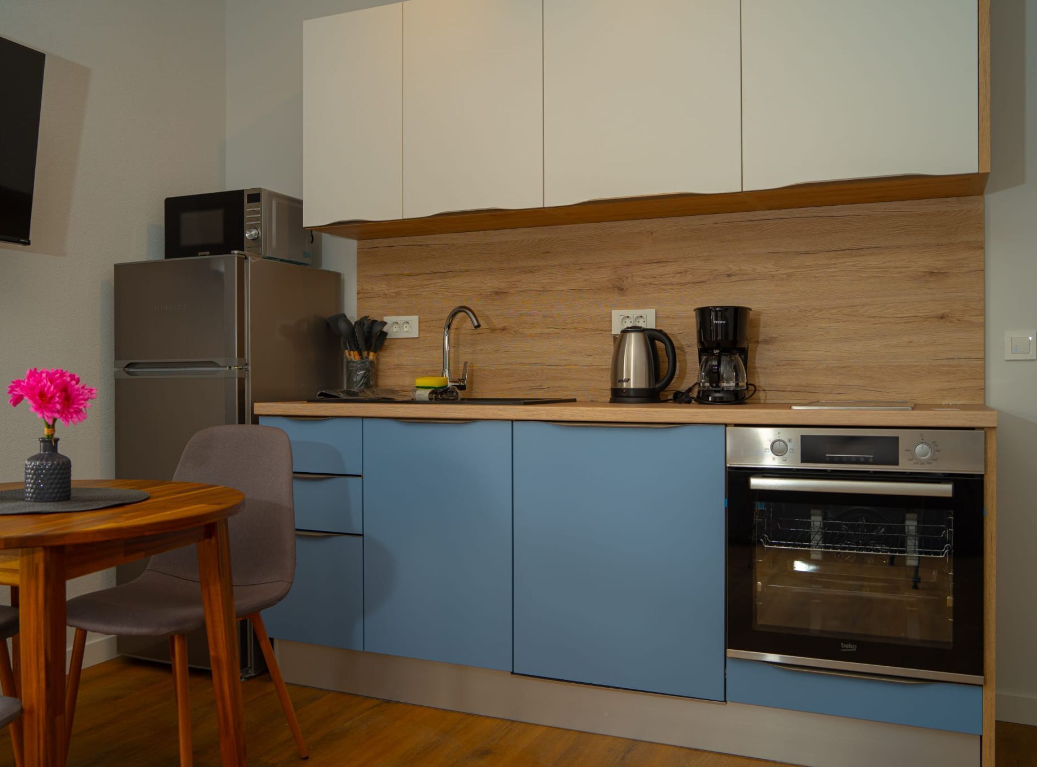 Cocina compacta con refrigerador, microondas, cafetera y horno.