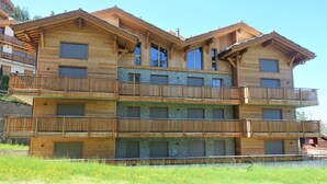 A multi-story wooden building with balconies and large windows.