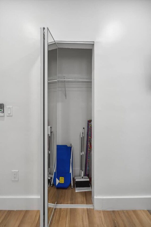 A room with a white wall, a wooden floor, a blue storage unit, and a metal ladder.