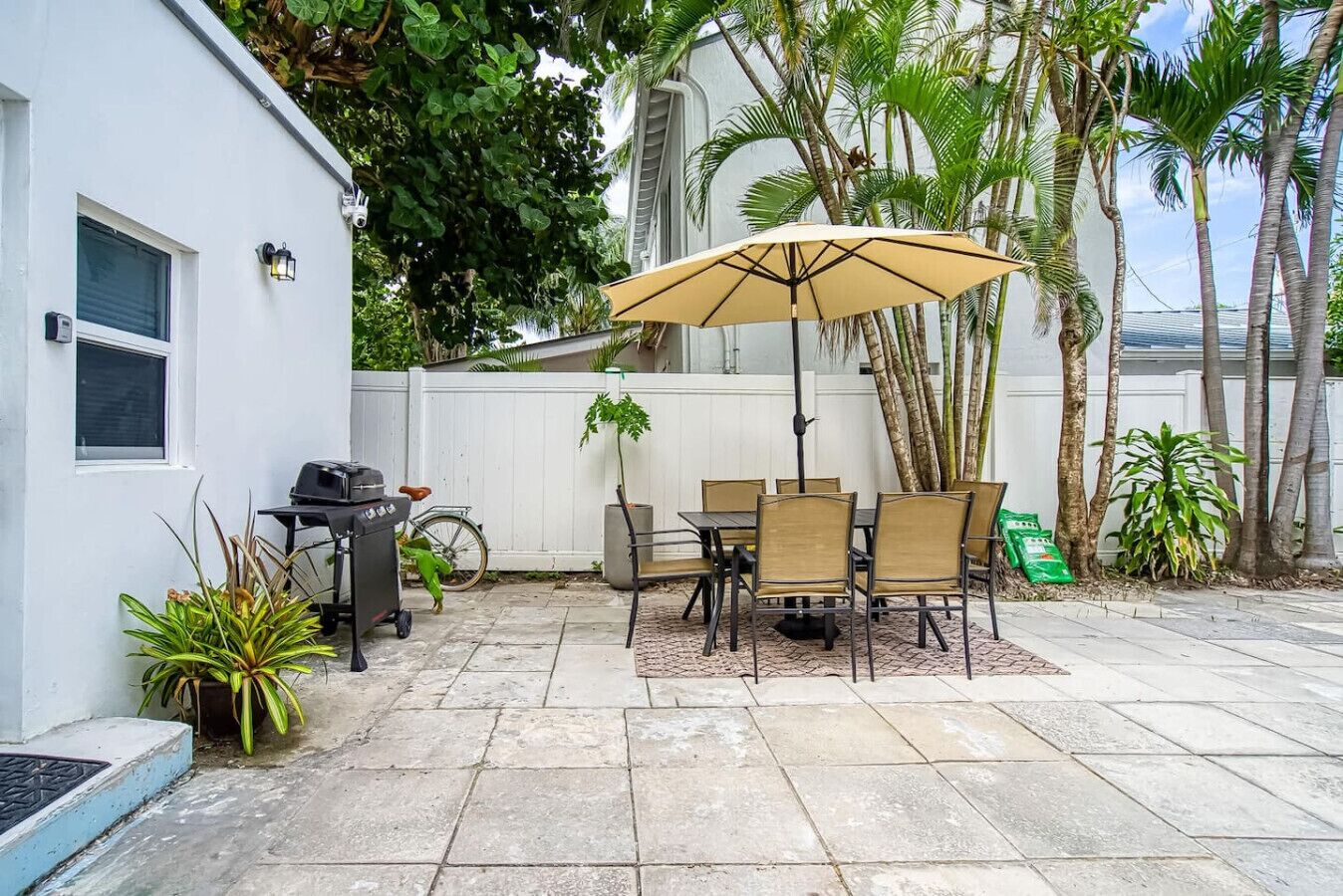 A patio with a table and chairs, a grill, and a bicycle.