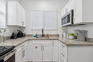 A modern kitchen with white cabinets, a granite countertop, a built-in microwave, and a stainless steel range hood. - Casa Roselle full 2/2 (Hollywood)