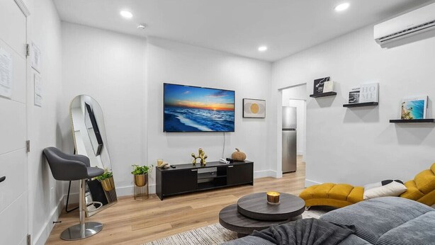 A modern living room with a flat-screen TV, a sofa, a coffee table, and a mirror. - Casa Roselle full 2/2 (Hollywood)