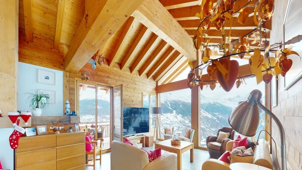 A cozy wooden interior with a sofa, a TV, and a view of snow-capped mountains. - Etoiles des Neiges Luxe & Jacuzzi Chalet (Heremence)