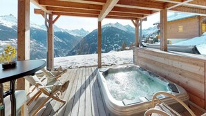 A wooden deck with a hot tub, wooden chairs, and a table. - Etoiles des Neiges Luxe & Jacuzzi Chalet (Heremence)