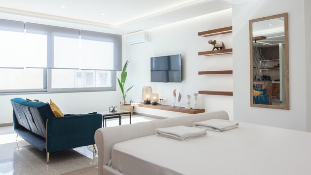 A modern hotel room with a large bed, a sofa, a TV, and a mirror. - Stylish Modern Suite at Piraeus Port (Piraeus)