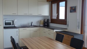 A compact kitchen with white cabinets, a microwave, a coffee maker, and a window with a view. - Pleasant Apartment With Balcony (Veysonnaz)