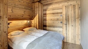 A wooden cabin room with a bed, wooden walls, and a sloped ceiling. - Lovely Apartment Near ski Lift (Anniviers)