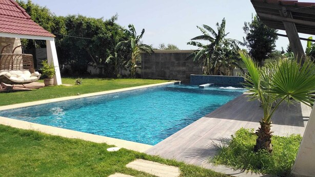 A rectangular swimming pool with a tiled edge, surrounded by a grassy lawn and a concrete deck. - VILAA TEJ EL MOULK (Somâa)