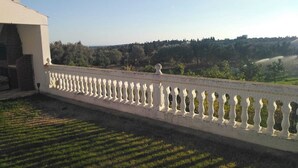 A building with a white balcony and a view of a green landscape. - VILAA TEJ EL MOULK (Somâa)