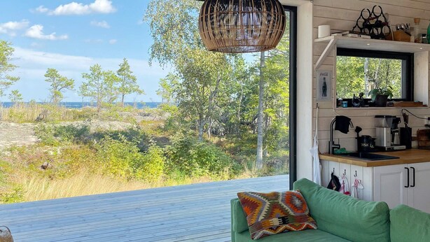 Ein modernes Wohnzimmer mit einem grünen Sofa, einem Holztisch und Blick auf eine natürliche Landschaft.
