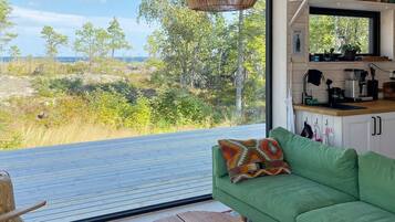 A modern living space with a green sofa, a wooden coffee table, and a view of a natural landscape.