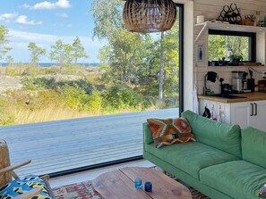 A modern interior with a green sofa, a wooden coffee table, and a view of a natural landscape. - 4 Star Holiday Home in Vaddo (Väddö)