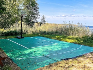 An outdoor basketball court with a net, surrounded by trees and a view of the sea. - 4 Star Holiday Home in Vaddo (Väddö)