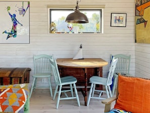 A dining area with a round wooden table, four light blue chairs, and a hanging pendant light. - 4 Star Holiday Home in Vaddo (Väddö)