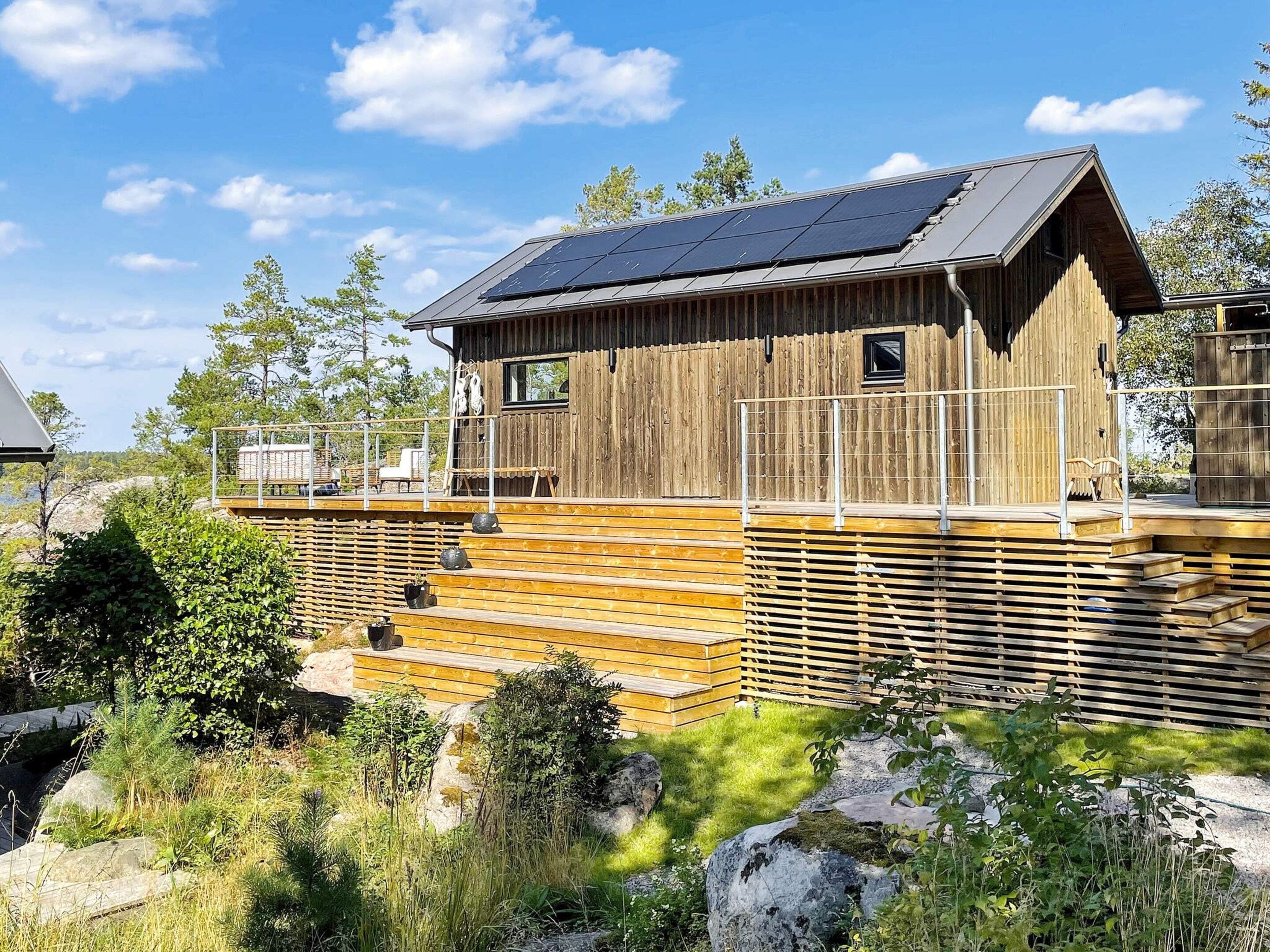 A wooden cabin with a sloped roof, a deck, and a small window.