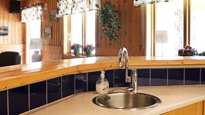 A kitchen with wooden cabinets, a stainless steel sink, and a dishwasher. - 4 Star Holiday Home in Oskarstrom (Oskarstrom)