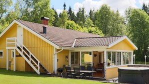 A yellow building with a covered patio, a staircase, and a hot tub. - 4 Star Holiday Home in Oskarstrom (Oskarstrom)