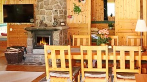 A cozy wooden interior with a stone fireplace, wooden dining table, and chairs. - 4 Star Holiday Home in Oskarstrom (Oskarstrom)