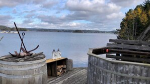 En träbrygga med en tunna, lyktor och en bänk, med utsikt över en stilla sjö.