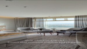 A modern hotel room with a large bed, two armchairs, a coffee table, and a view of the city. - Heaven inn 1 (Abha)