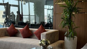 A modern living room with a glass coffee table, a sofa with red cushions, and a large potted plant. - Heaven inn 1 (Abha)