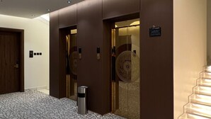 A hotel lobby with a stone-patterned floor, a wooden door, and a staircase. - Heaven inn 1 (Abha)