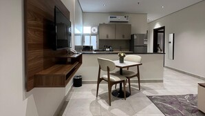 A modern kitchen with built-in appliances, a dining area with a table and chairs, and a flat-screen TV mounted on the wall. - Heaven inn 1 (Abha)