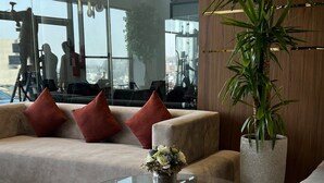 A modern living room with a glass coffee table, a sofa with red cushions, and a large potted plant. - Heaven inn 1 (Abha)