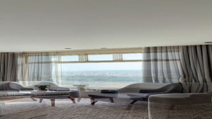 A modern hotel room with a large bed, two armchairs, a coffee table, and a view of the city. - Heaven inn 1 (Abha)