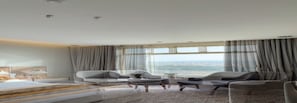 A modern hotel room with a large bed, two armchairs, a coffee table, and a view of the city. - Heaven inn 1 (Abha)