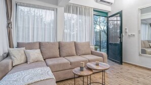 A modern living room with a beige sectional sofa, two round side tables, and a large mirror on the wall. - Hidden Gem Holiday Home With Pool in Kastel Stafilic (Kastela)