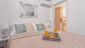 A bedroom with a bed, pillows, a tray with a croissant and drinks, a bedside lamp, and a mirror on the wall. - Hidden Gem Holiday Home With Pool in Kastel Stafilic (Kastela)