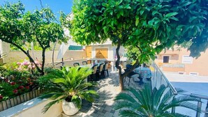 A courtyard with a dining area, potted plants, and a staircase leading to an upper level. - Mastrinka Bright Apartment With Free Parking and Modern Amenities (Trogir)