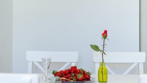 A table with a plate of strawberries, a glass vase with a red rose, and a clear glass. - Seaside Getaway Holiday Home With Patio Slatine (Split)