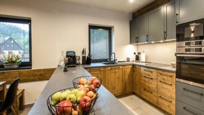 A modern kitchen with wooden cabinets, stainless steel appliances, and a fruit bowl on the counter. - Holiday Villa in Beautiful Location (Bedrichov)