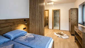A modern bedroom with two beds, a wooden wardrobe, a mirror, and a fur rug. - Holiday Villa in Beautiful Location (Bedrichov)