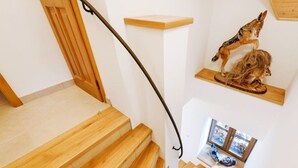 A wooden staircase with a handrail, a wooden door, and a wall-mounted shelf with a fox and a squirrel sculpture. - Beautiful Villa With Activities (Varvažov)