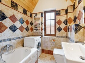Ein Badezimmer mit Waschmaschine, Badewanne und Waschbecken.