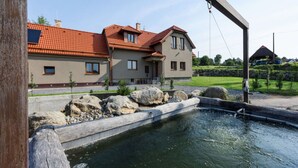 A two-story house with a red-tiled roof, a stone facade, and a small pond in the foreground. - Beautiful Villa With Activities (Varvažov)