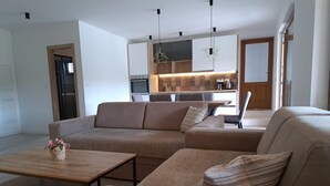 Un soggiorno moderno con un divano componibile, un tavolino in legno e una cucina sullo sfondo.