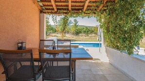 Una veranda coperta con una piscina, due sedie e un tavolo.