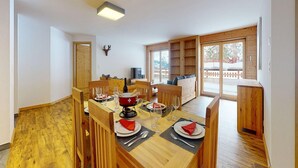 A dining area with a wooden table set for four, a mounted deer head on the wall, and a view of the outdoors through a sliding glass door. - Apartment With Comfortable Arrangements (Veysonnaz)