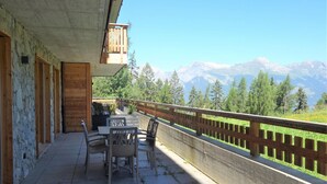 A balcony with a table and chairs, overlooking a mountainous landscape. - Apartment With Comfortable Arrangements (Veysonnaz)